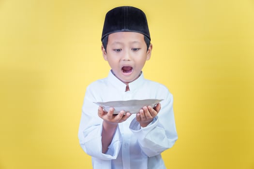 An asian boy looks enthusiastically at the plate in his hand, the concept of Ramdan Kareem celebration. photo