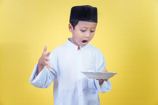 An asian boy looks shocked at the plate in his hand, the concept of Ramdan Kareem celebration. photo