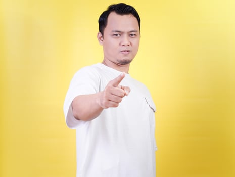 An asian man confidently points forward against a bright yellow background. photo
