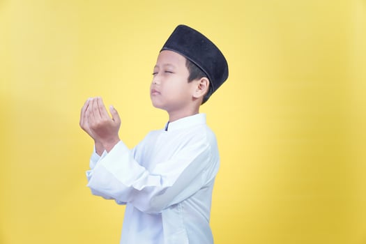 muslim boy praying on yellow background photo