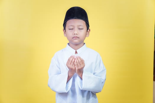 A young asian boy in prayer attire reflects the spirit of Ramadan Kareem with devotion photo