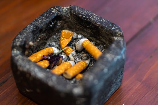 Used Cigarette Butts in Ashtray on Wooden Surface photo