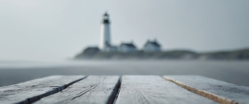 close up of empty wooden table with blurred lighthouse on shore background photo