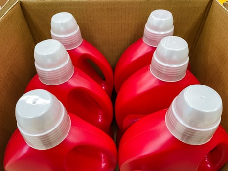 Inside a sturdy and wellconstructed box, there are four vibrant red bottles with shiny white caps, securely stored and meticulously prepared for transport to carry various types of liquids photo