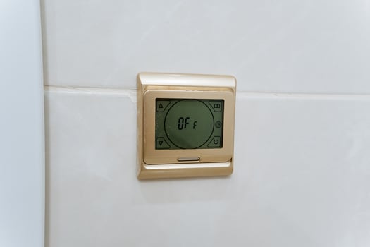 A modern digital thermostat is elegantly mounted on a pristine white tiled wall, seamlessly blending cuttingedge technology with stylish design in a contemporary and inviting living space photo