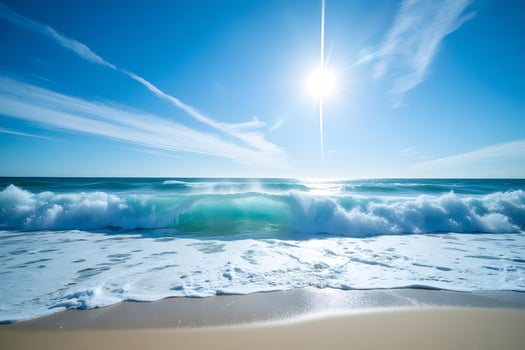 Ocean waves crashing onto a sandy beach under a bright sun with a clear blue sky and scattered clouds photo