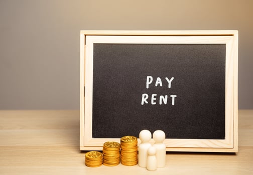 The concept of paying rent for housing, house or apartment. Accumulating money and saving. Miniature family standing near a board with the word Pay rent. photo