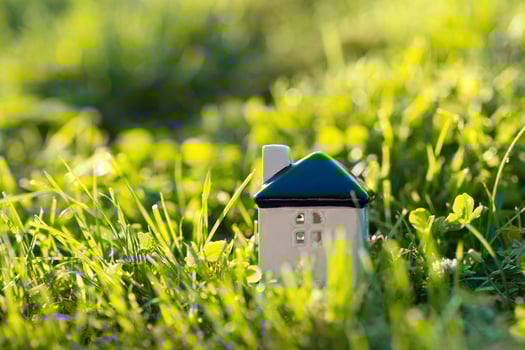 Miniature white house on a green grass. Real estate concept. Eco-friendly home. Buying a housing outside the city. Selective focus photo