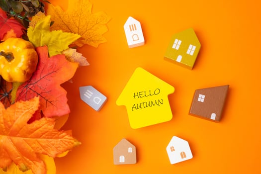 Miniature houses with the inscription hello autumn and fall leaves. Concept of beginning of new autumn season. Real estate and housing. Flat lay photo
