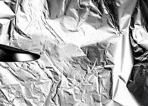 High-contrast crumpled aluminum foil texture with reflective and wrinkled details, perfect for abstract designs. photo