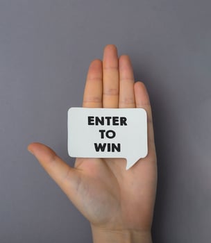 Person holds on palm white sticker with words Enter to Win photo
