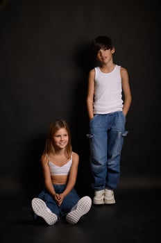 Two young models, an Asian boy and a blonde girl, pose in a well-lit studio. Their contrasting looks and expressive faces create a visually captivating portrait. photo