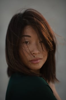 A captivating Asian woman looks into the distance, her face softly illuminated by golden light. photo