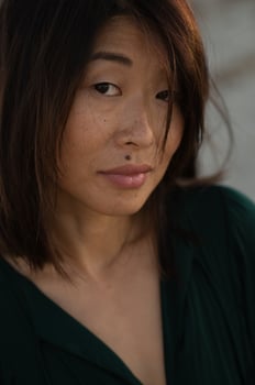 A stunning Asian woman with a beauty mark above her upper lip gazes softly in the golden sunset light. photo