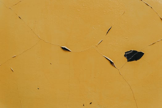 A yellow wall with a crack in it and a leaf on it photo