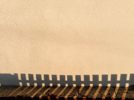 A fence casts a shadow on a wall photo