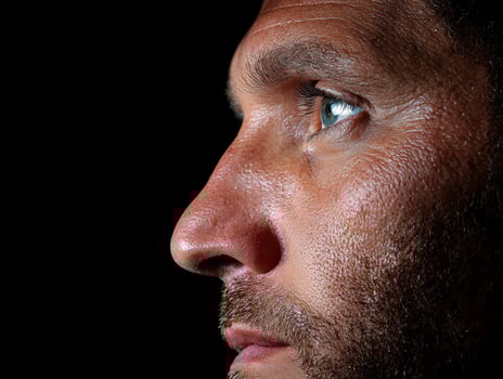 Close up profile of a mans face, showing his eye and stubble photo