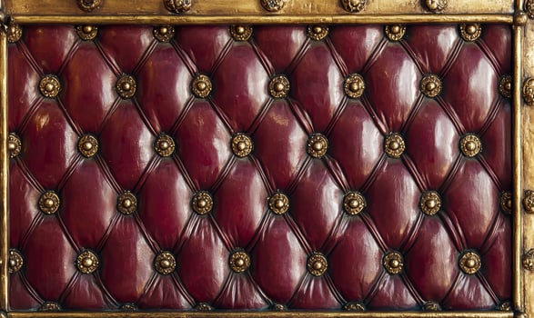 Red leather tufted upholstery with gold accents photo