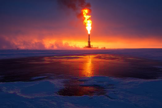 Gas plant burning during colorful sunset in snowy landscape. photo