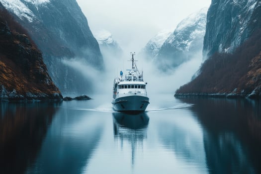 Expedition yacht sailing in norwegian fjord with snowy mountains in background. photo