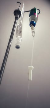 Close-up of iv drip against gray hospital wall, highlighting medical equipment used in patient care and treatment photo