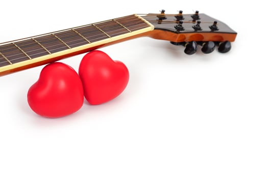 Acoustic guitar neck and red heart against white background. Love, entertain and music concept. photo