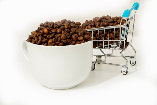 Coffee beans in a cup beside a mini shopping cart photo