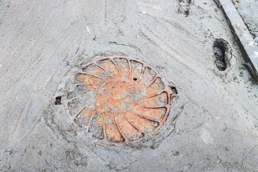 rusty sewer manhole cover on poorly concreted pat photo