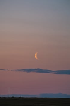 Delicate crescent moon hangs low in a pastel-colored sky, with soft hues of pink and blue blending seamlessly at dusk. Snaefellsnes peninsula, west Iceland photo