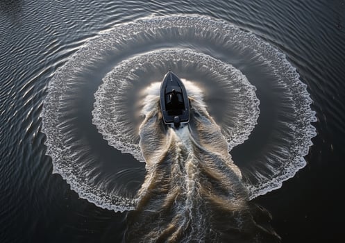 Boat creating circular ripples in tranquil water during a sunny day photo