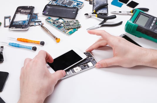 Electronics repair service. Repairman disassembling smartphone for inspecting. Technician fixing broken phone, copy space for text photo