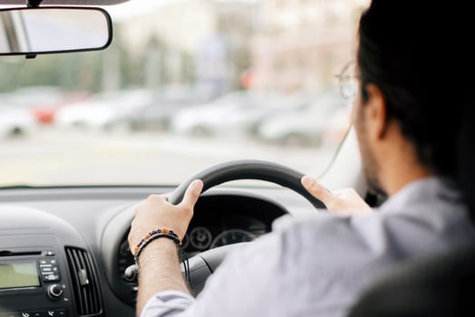 Rear view of indian long-haired man experienced driver driving auto, looking at road, copy space, shot from automobile back seat, closeup. Unrecognizable arab man enjoying his brand new car photo