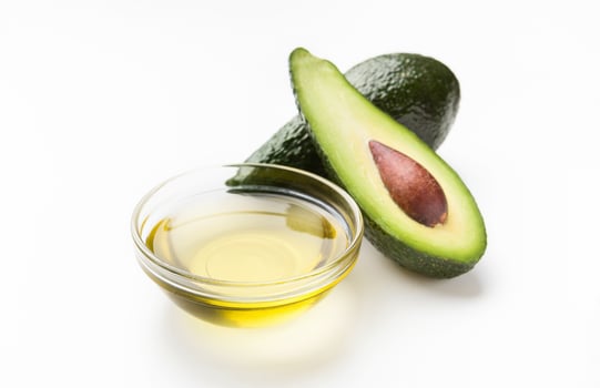 Fresh avocado and oil in glass bowl on white background. Vegetable fats concept photo