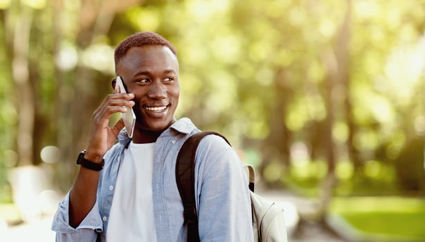 Portrait of handsome African American man talking to his friend on cellphone at green park photo