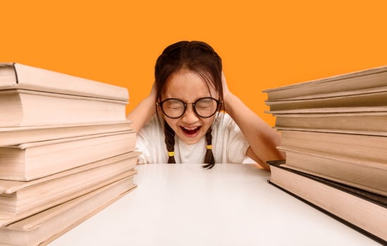 Unhappy Asian Schoolgirl Crying Sitting At Books Doing Homework Over Yellow Background. Studio Shot photo