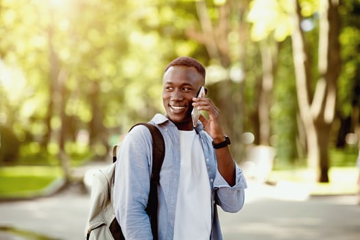 Portrait of handsome African American man talking to his friend on cellphone at green park photo