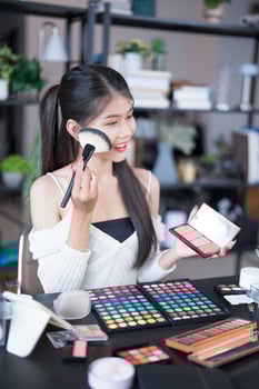 a woman is holding a makeup brush and makeup products. photo