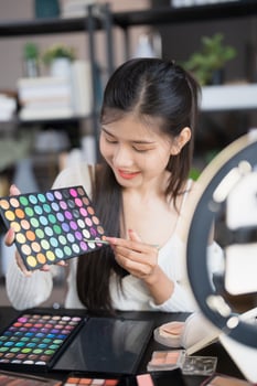 beauty and cosmetics, makeup and beauty concept - asian woman holding makeup palette and looking at photo