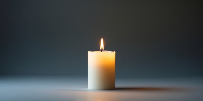 The glowing flame of the burning candle casts a warm candlelight into the darkness. photo