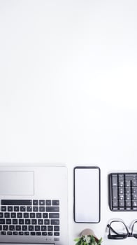 Top View of Workspace with Laptop, Keyboard, Mobile Phone on White Background photo