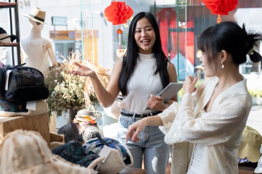A smiling, service-minded Asian female shop employee is recommending new items to a customer. photo