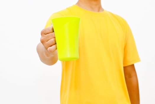 Bright yellow t-shirt, person holding a radiant green drinking cup against a white background photo