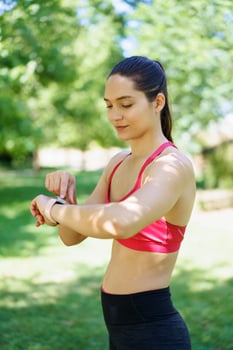 A woman wearing a fitness tracker is exercising in a park, emphasizing her focus on health and wellness photo