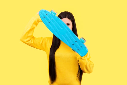 girl with blue skateboard on yellow photo