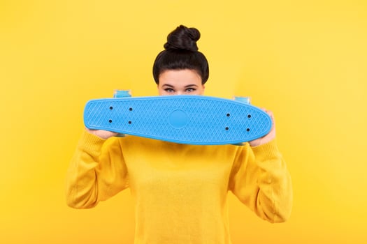 cute girl with blue skateboard on yellow photo