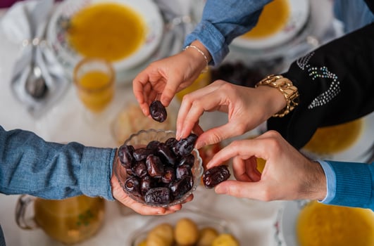Happy Muslim family having iftar dinner to break fasting during Ramadan dining table at home group of Islamic people eating a healthy food dates together sharing and giving. photo