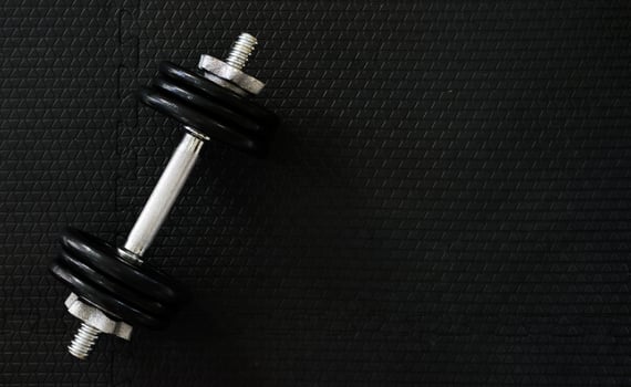 Top view of Iron dumbbells or weights on black floor with copy space for text on right photo