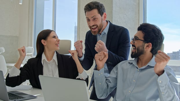 Happy creative team celebrate victory in office successful sales stock market data online business people businessmen and businesswoman winning teambuilding corporate teamwork with documents laptop photo