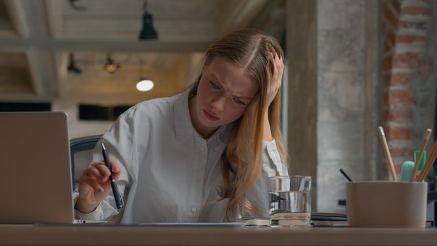 Stressed Caucasian office female worker woman student girl work reading documents writing report studying businesswoman business problem stack stats stress migraine headache overworked at workplace photo