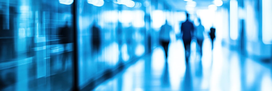 Individuals in business attire navigate a busy corridor in an office building filled with natural light photo